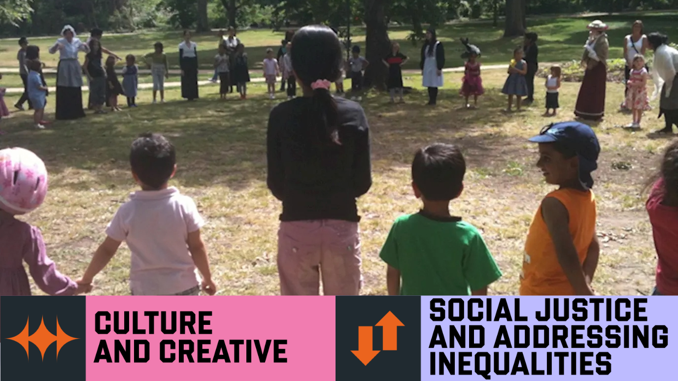 Hn Project Participation Image - group of people and children standing in large circle on grass - 'Culture and Creative'and ‘Social Justice and Addressing Inequalities’  Research strength graphic banner