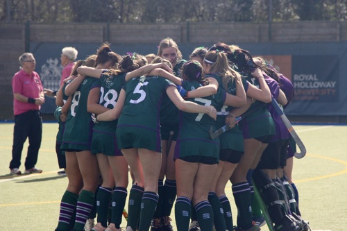 Women's hockey team huddle on the pitch